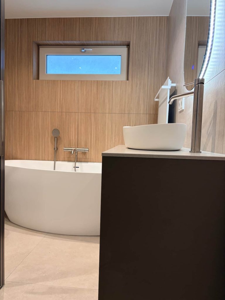 Zijaanzicht van bad en wastafelmeubel met daglicht uit hoog raam