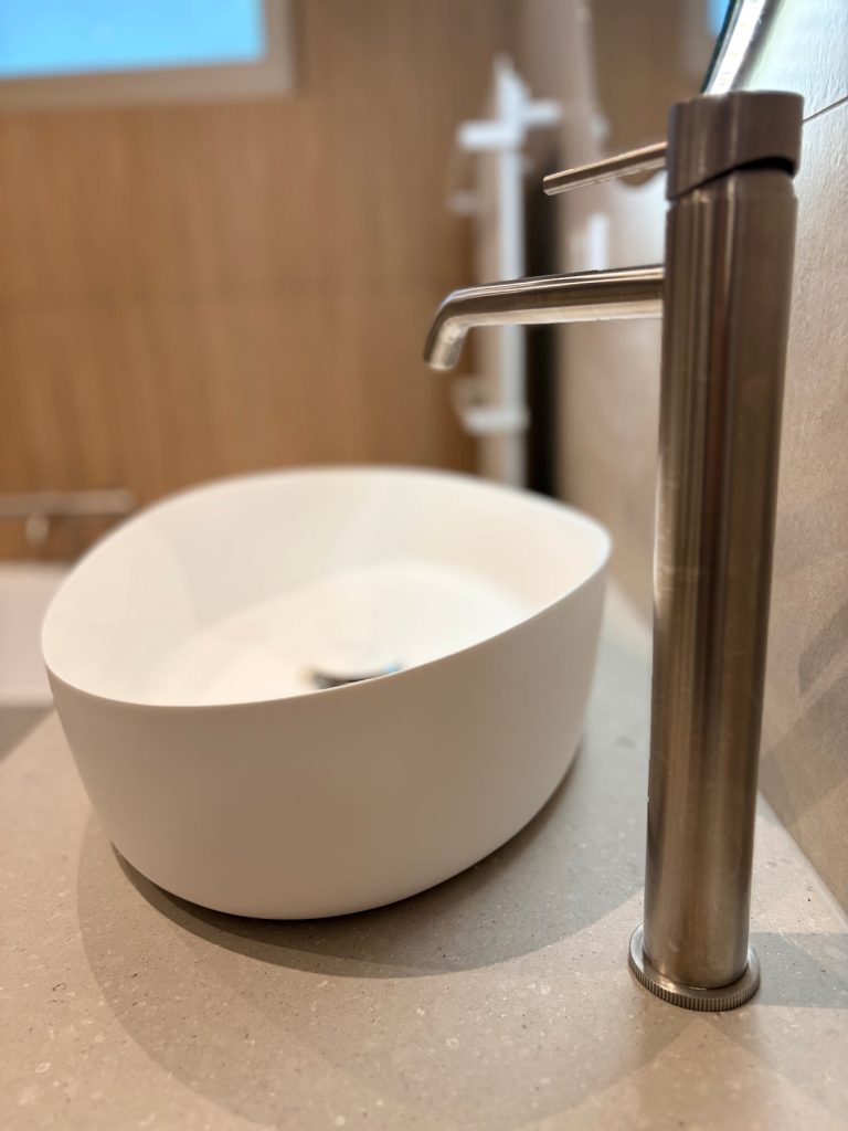 Close-up van witte waskom met hoge rvs kraan op natuursteen blad