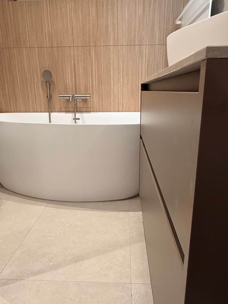 Vrijstaand bad tegen houtlook wand met rvs kraan en daglicht