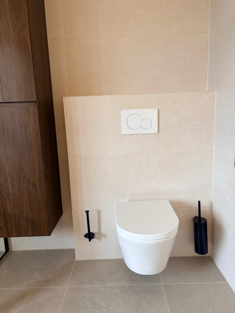 Hangend toilet met witte Geberit bedieningsplaat en zwarte toiletaccessoires in luxe badkamer Waalre