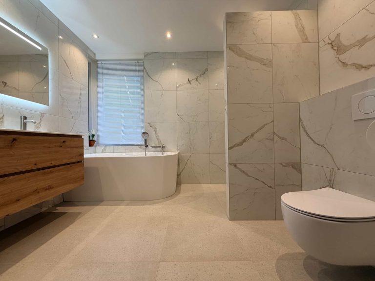 Overzicht van een lichte marmerlook badkamer met halfvrijstaand bad, zwevend houten meubel en hangend toilet