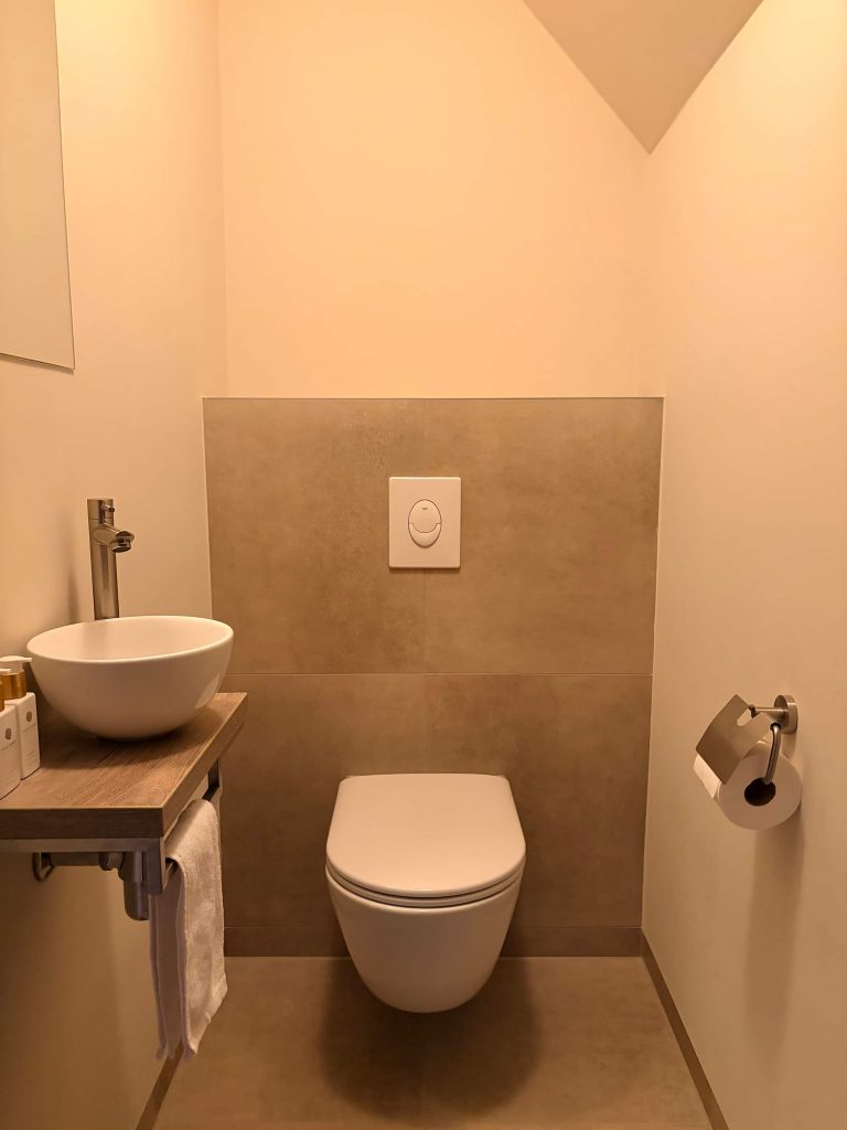 Apart toilet in Best met hangend toilet, betonlook accentwand en zwevend houten plateau met witte fonteinkom