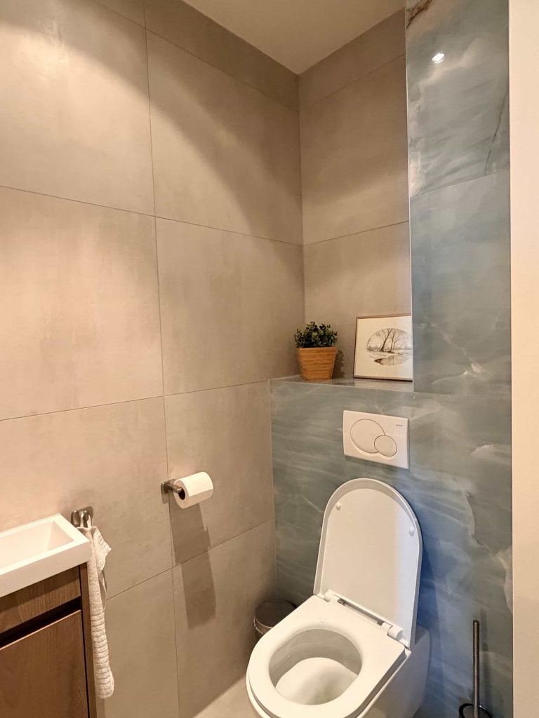 Apart toilet met fonteintje en blauwe onyx-look accent na badkamerrenovatie in Eindhoven