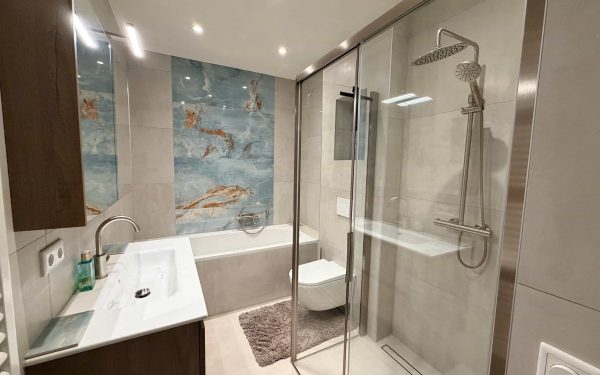 Compacte badkamer in Eindhoven met bad, inloopdouche en blauwe onyx-look tegel na renovatie