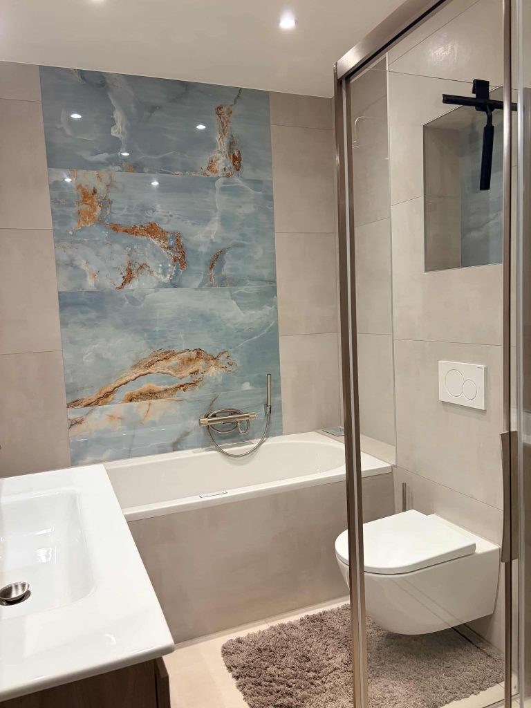 Nieuwe badkamer in Eindhoven met blauwe onyx-look tegels achter het bad en zwevend toilet