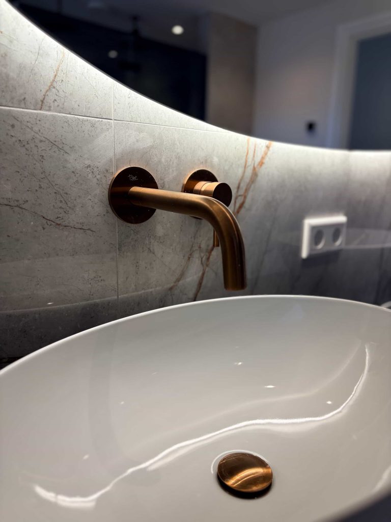 Detail van bronskleurige wandkraan en witte waskom in luxe badkamer in Helmond
