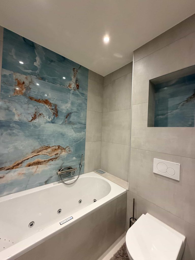 Bubbelbad met blauwe onyx-look achterwand en inbouwnis in badkamer in Eindhoven