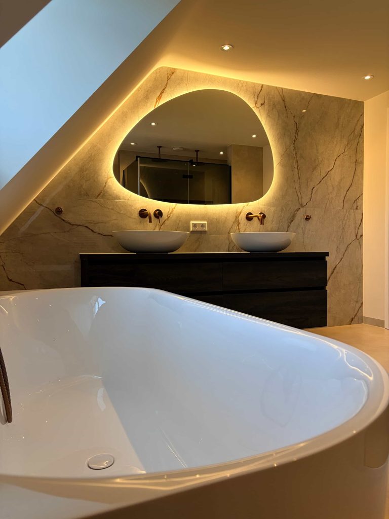 Vrijstaand bad in luxe badkamer renovatie in Helmond met marmerlook wand en verlichte spiegel