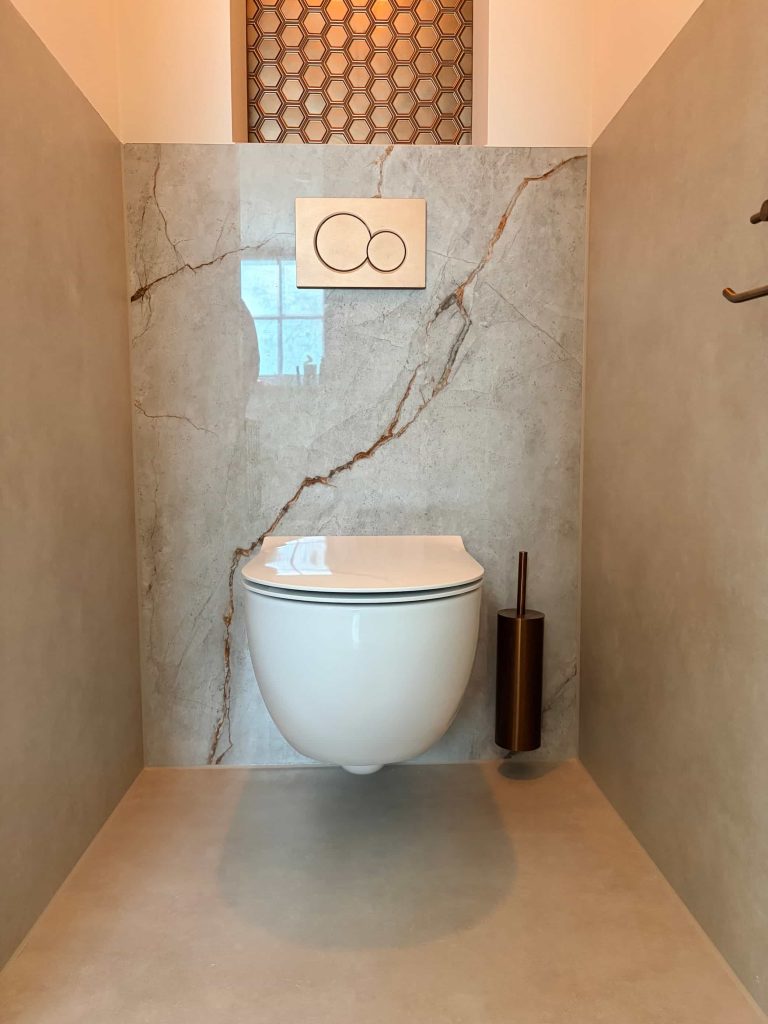 Zwevend toilet met marmerlook achterwand en verlichte honingraatnis in project in Helmond