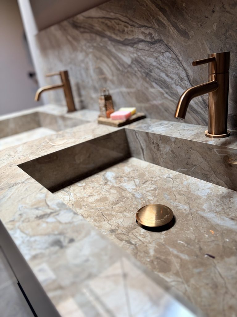 Wastafel in taupe marmerlook met koperkleurige kraan en afvoerplug